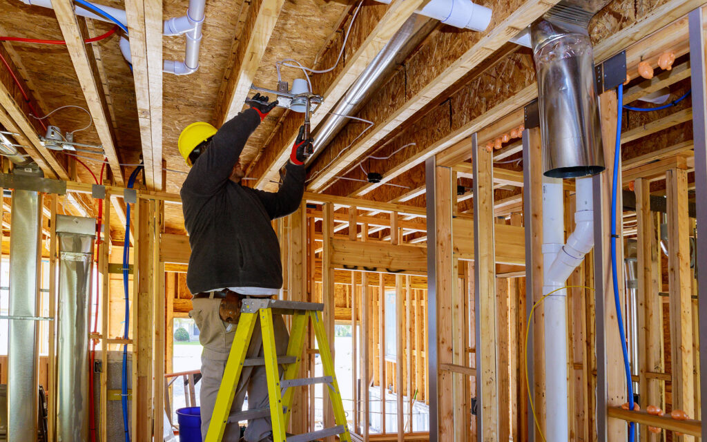 The electrician nailing to the ceiling lamp, installs the lighting lamp in the laying ceiling