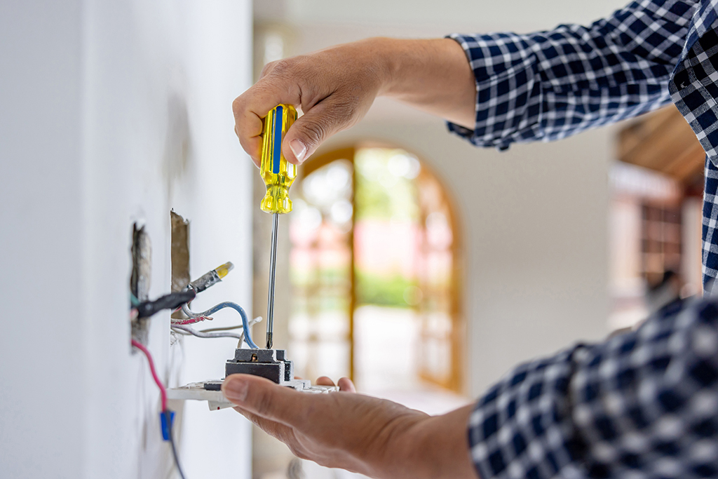 Close-up on an electrician installing a power outlet while remodeling a house - home improvement concepts